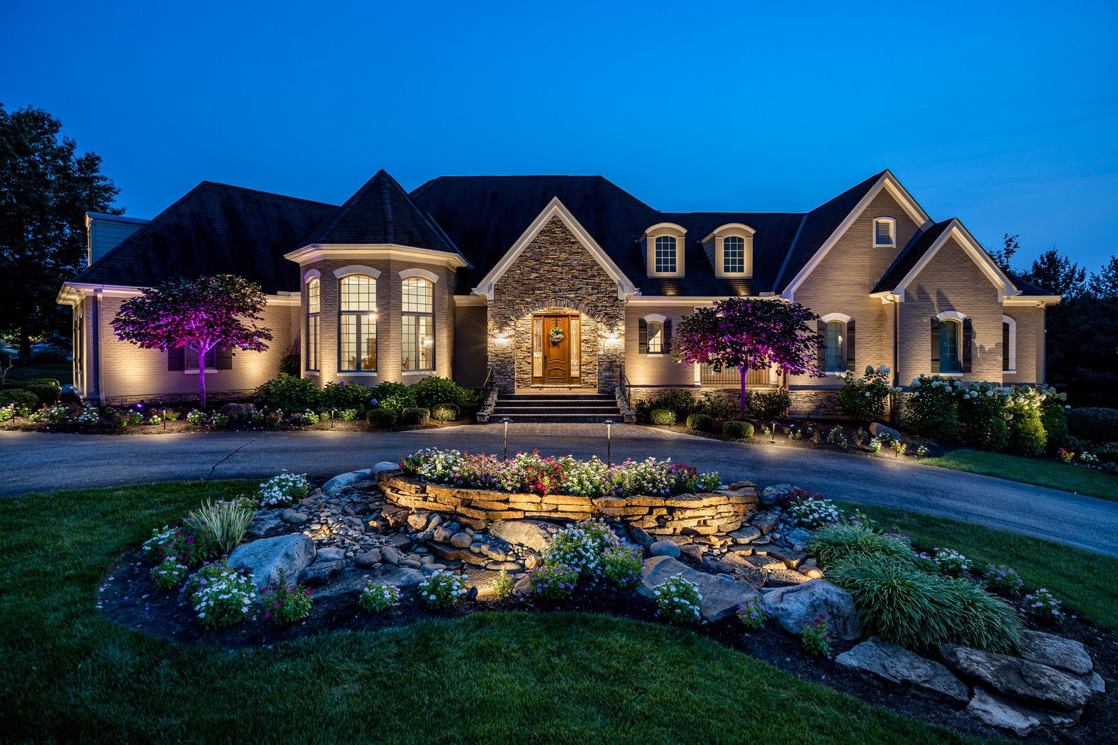 A large house with lights on the front yard.
